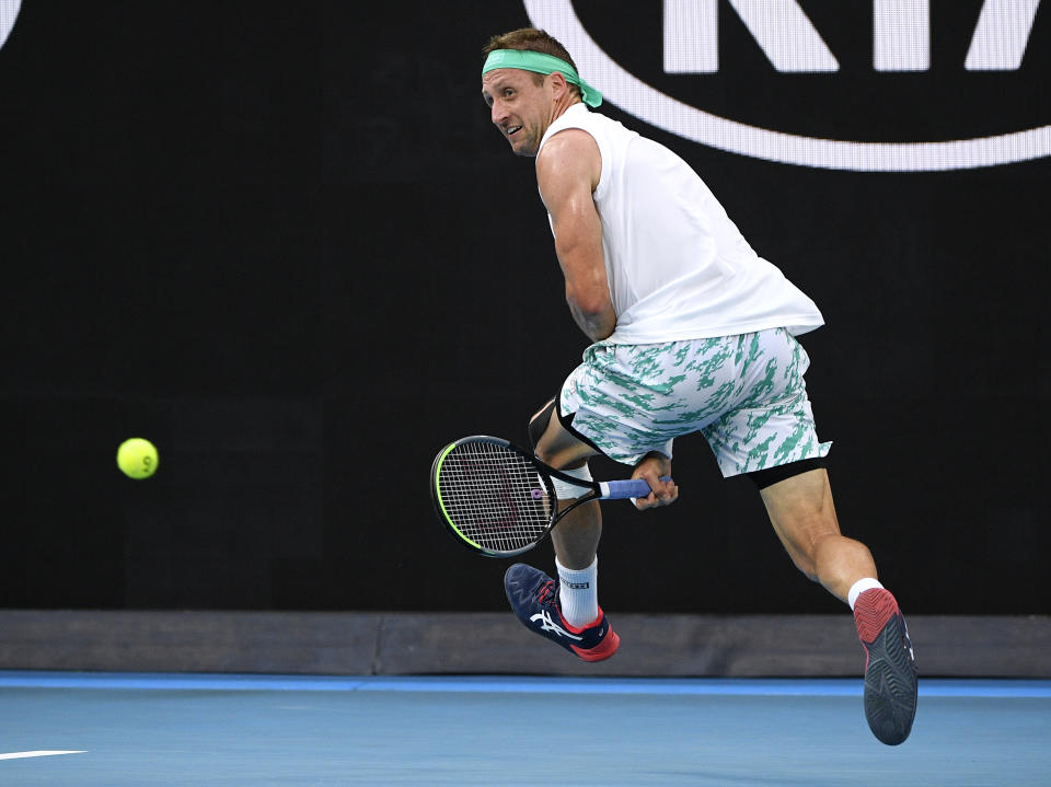 Tennys Sandgren of the U.S. plays a shot back between his legs to Italy's Fabio Fognini during their fourth round singles match at the Australian Open tennis championship in Melbourne, Australia, Sunday, Jan. 26, 2020. (AP Photo/Andy Brownbill)