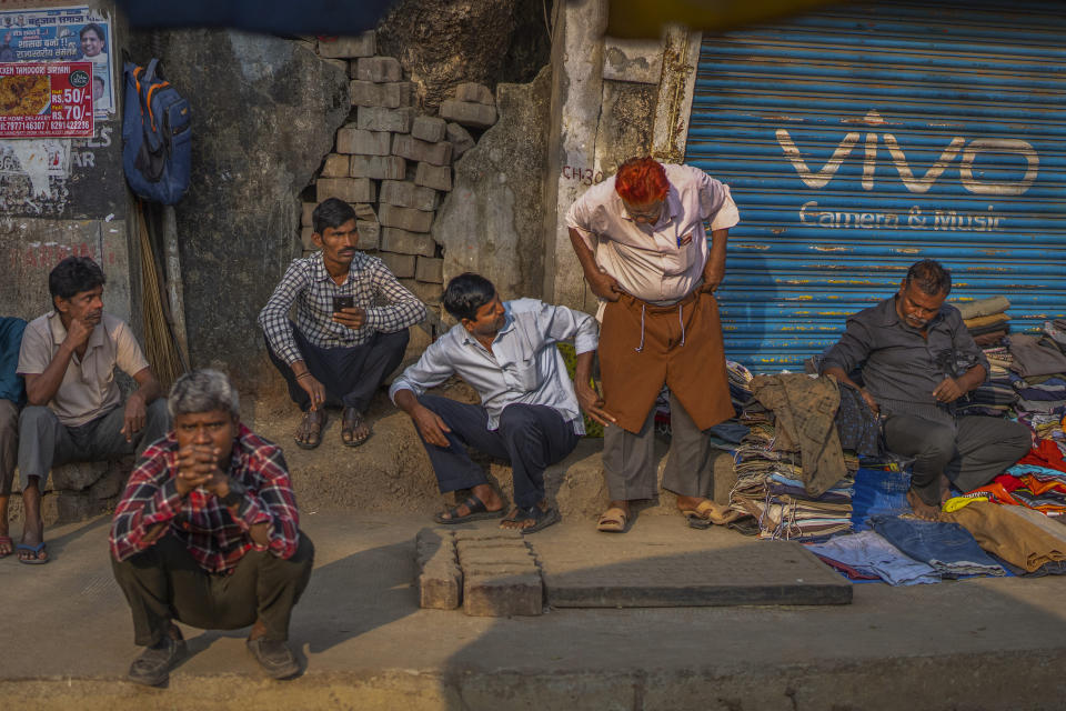 An Indian daily wage laborer tries shorts from a roadside vendor as he waits with others to get hired in Mumbai, India, Wednesday, Feb. 1, 2023. Indian Prime Minister Narendra Modi's government ramped up capital spending by a substantial 33% to $122 billion in an annual budget presented to Parliament on Wednesday, seeking to spur economic growth and create jobs ahead of a general election next year. (AP Photo/Rafiq Maqbool)