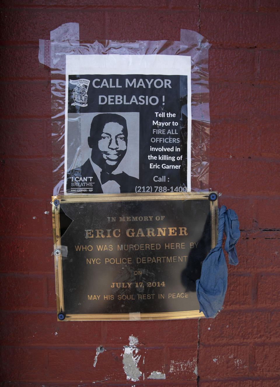 A sign and plaque are mounted on a wall at the sidewalk area where Eric Garner was apprehended by police in the Staten Island borough of New York, Tuesday, July 16, 2019. Federal prosecutors won't bring charges against New York City police officer Daniel Pantaleo in the 2014 chokehold death of Garner. (AP Photo/Mark Lennihan)