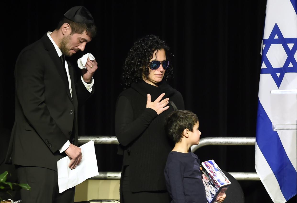 In this Dec. 21, 2017 file photo, Jonathon Sherman wipes his tears as he and his sister Lauren walk to the stage during a memorial service in Mississauga, Ontario, for their parents Barry and Honey Sherman, who were found dead inside their mansion.