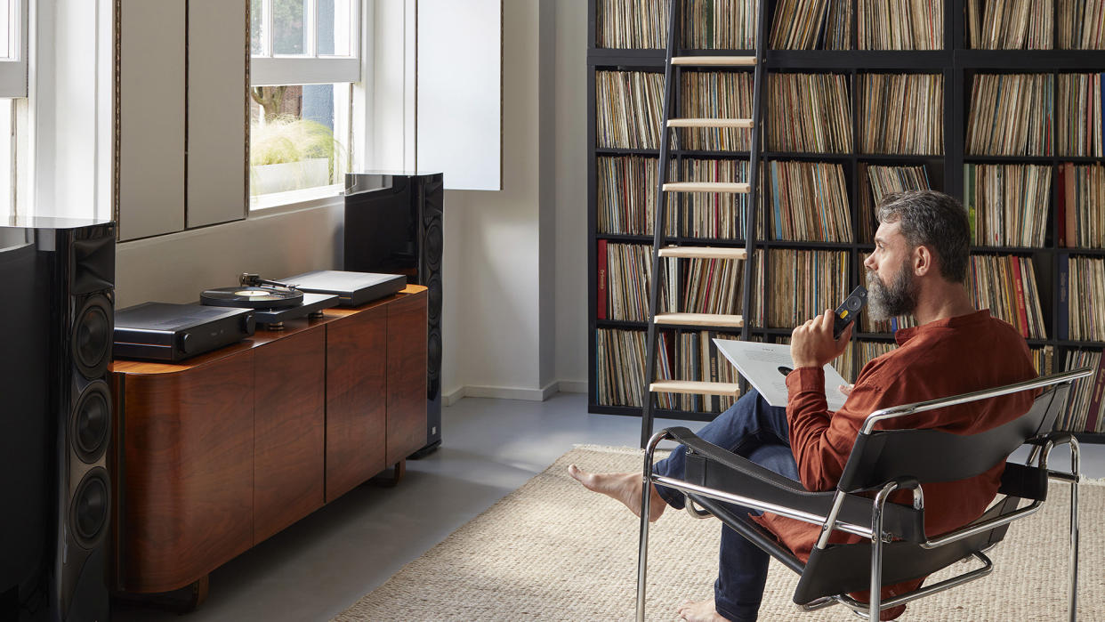  A man siting in a chair in front of the Radia music streamer and amplifier. 