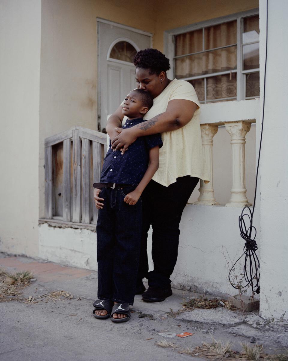 Kisha and LaDarayon leaning on a the balcony/fence of a home stood on the street