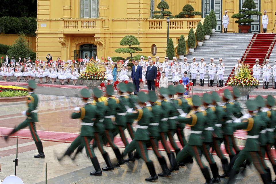 Japanese Prime Minister Yoshihide Suga, center left, and his Vietnamese counterpart Nguyen Xuan Phuc, center right, review an honor guard at the Presidential Palace in Hanoi, Vietnam Monday, Oct. 19, 2020. Suga is on an official visit to Vietnam. (AP Photo/Minh Hoang, Pool)