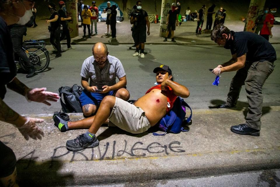 People help a man after he was shot with a rubber bullet under Interstate 35 during a protest over the police killing of George Floyd on May 30, 2020.