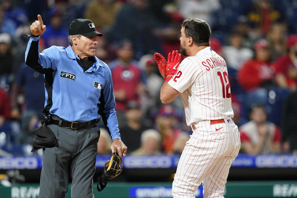 Philadelphia Phillies' Kyle Schwarber, right, reacts to umpire Angel Hernandez after striking out during the ninth inning of a baseball game against the Milwaukee Brewers, Sunday, April 24, 2022, in Philadelphia. (AP Photo/Matt Slocum)