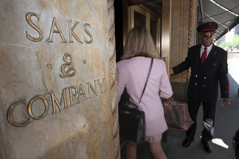 FILE — A Saks & Company doorman opens the 50th Street store entrance for customers, in New York, May 21, 1996. The parent company of Saks Fifth Avenue has signed a deal to buy upscale rival Neiman Marcus for $2.65 billion. The buyout was announced Thursday, July 4, 2024, after months of rumors that the department store chains had been negotiating a deal. (AP Photo/Richard Drew, File)