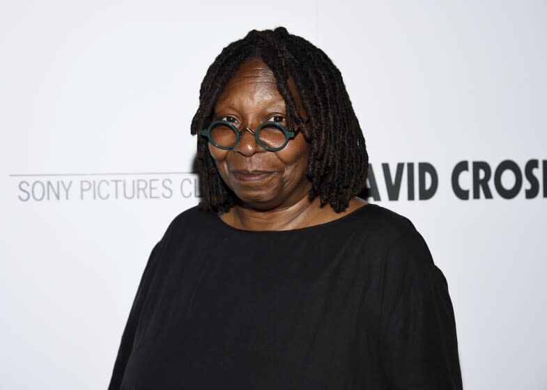 Whoopi Goldberg posing in round glasses and a black shirt