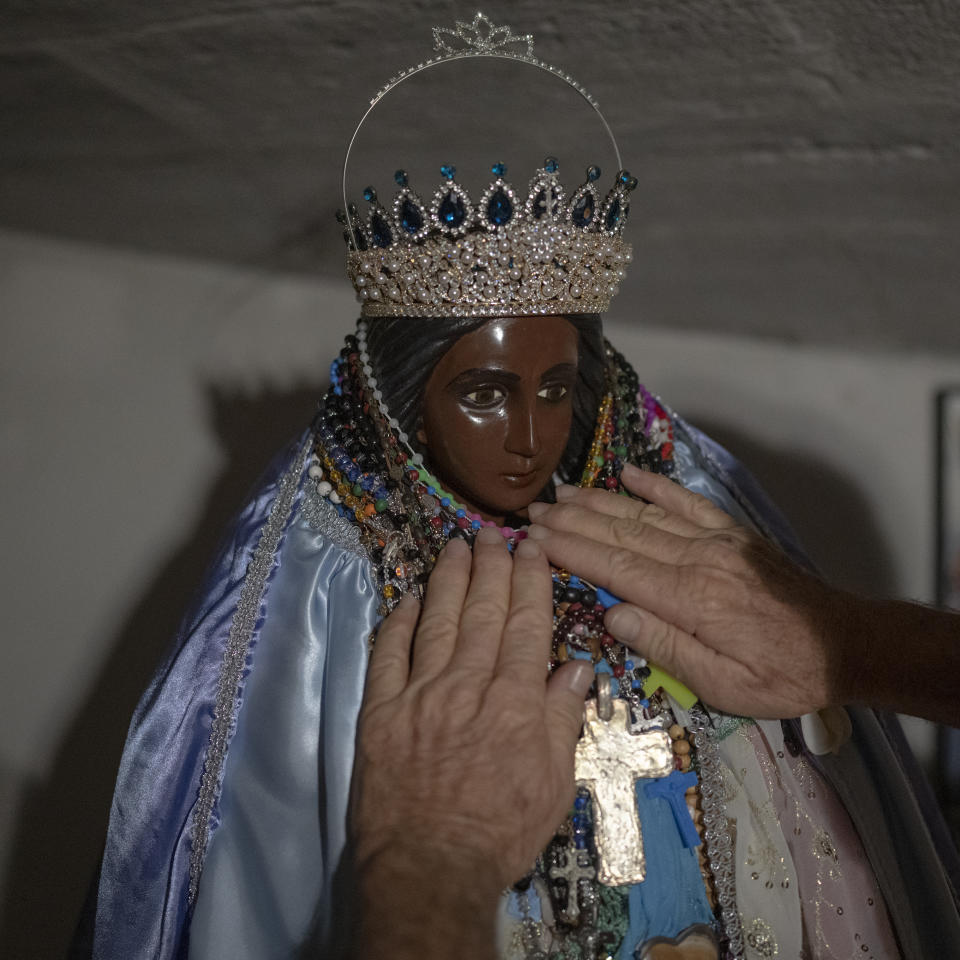 A man adorns a statue of Saint Sara with jewelry in the church of Saintes-Maries de la Mer, southern France, Sept. 23, 2022. Saint Sara is revered throughout Camarguaise folklore and tradition. (AP Photo/Daniel Cole)