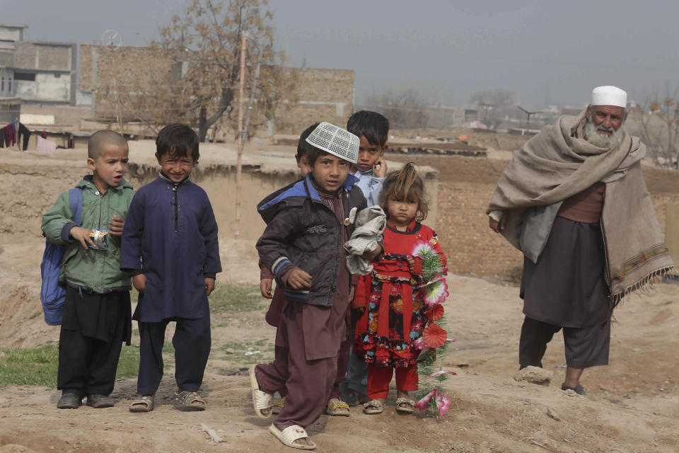 In this Thursday, Feb. 13, 2020 photo, Afghan refugees walk in the Kabobayan refugee camp, Peshawar, Pakistan. After 40 years, more than 1.5 million Afghan refugees still live in neighboring Pakistan. They feel abandoned by their own government, increasingly unwelcome in their reluctant host country and ignored by the United Nations. Many refugees have already tried going back to their homeland — lured by promises of help and hope from the international community and from Afghan President Ashraf Ghani — only to find there was neither food nor shelter for them. (AP Photo/Muhammad Sajjad)