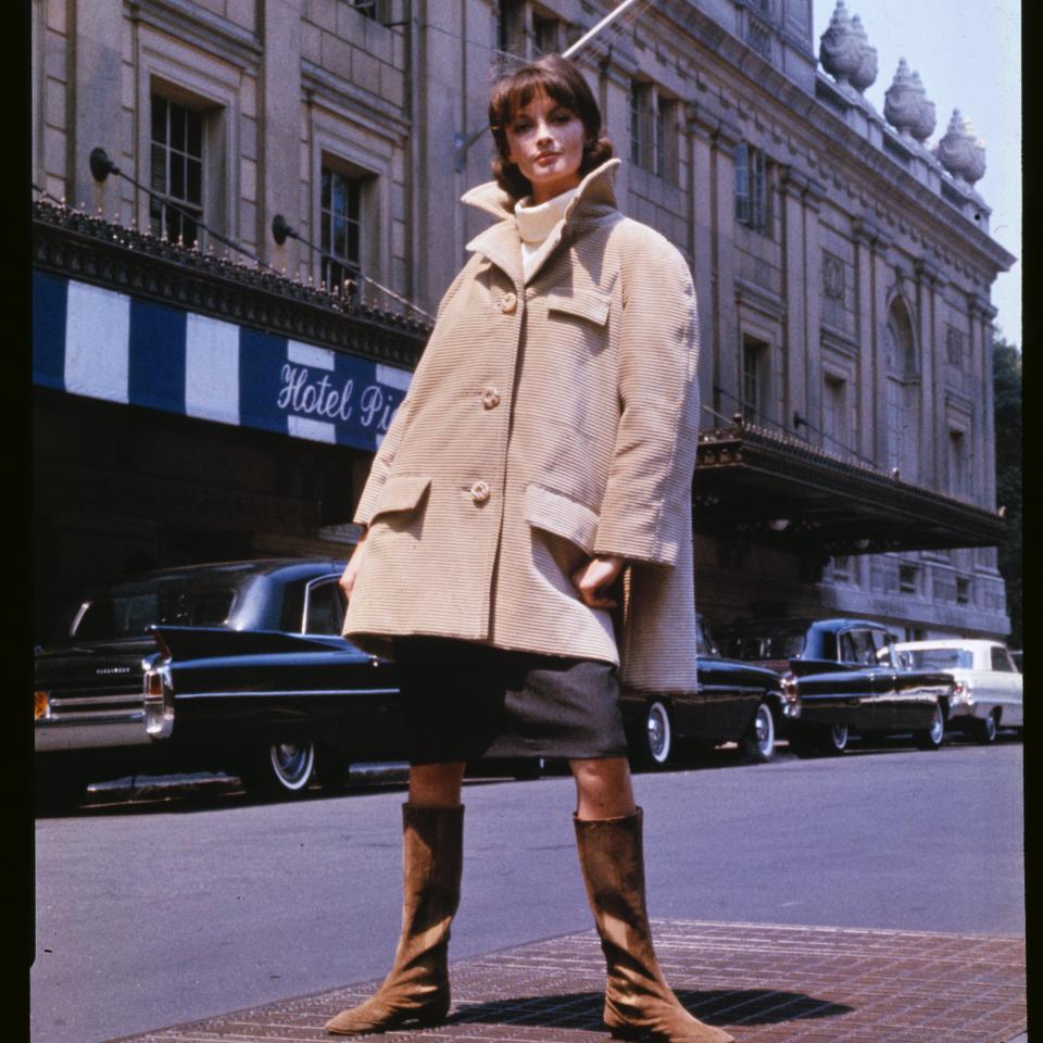 A person stands confidently on a city street in front of a building with a 