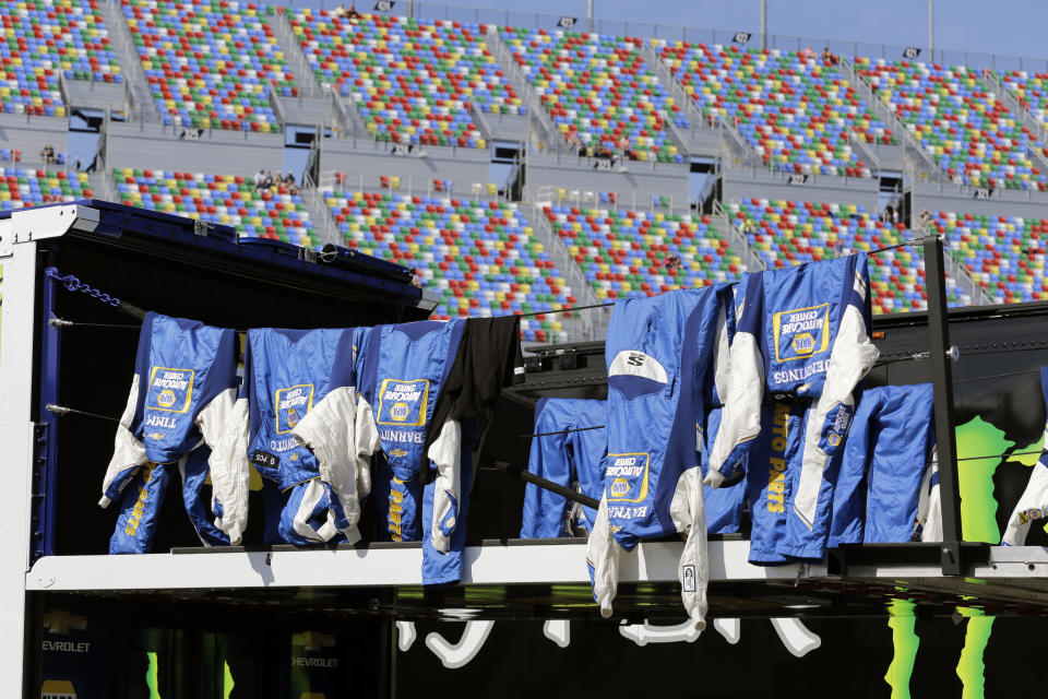 Crew members' fire suits dry out in the garage area before the restart of the NASCAR Daytona 500 auto race at Daytona International Speedway, Monday, Feb. 17, 2020, in Daytona Beach, Fla. Sunday's race was postponed because of rain. (AP Photo/Terry Renna)