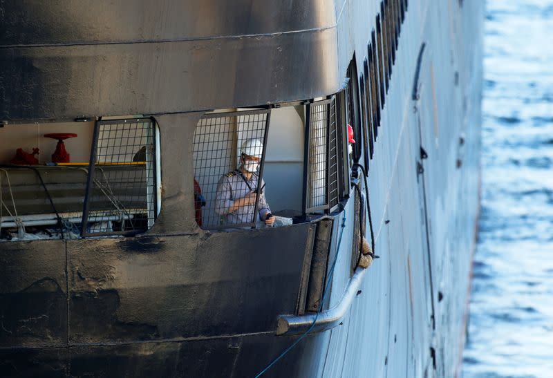 A crew member of the Zaandam of the Holland America Line cruise ships looks on as the vessel ties up at Port Everglades