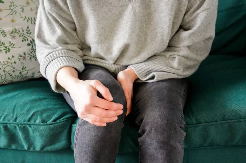 Person sitting holding their knee in pain