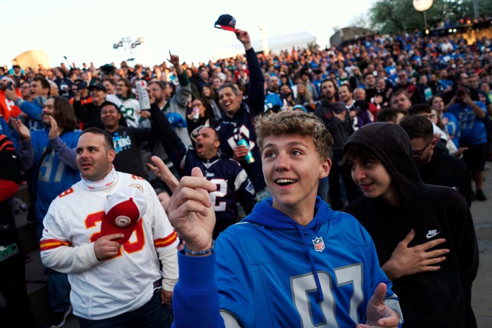 Daniel Itoney, center, of Shelby Township and Vata Margilaj, right, of Shelby Township, stand with others during the singing of the National Anthem and a fly over during the NFL Draft Experience at Hart Plaza in downtown Detroit on Thursday, April 25, 2024.