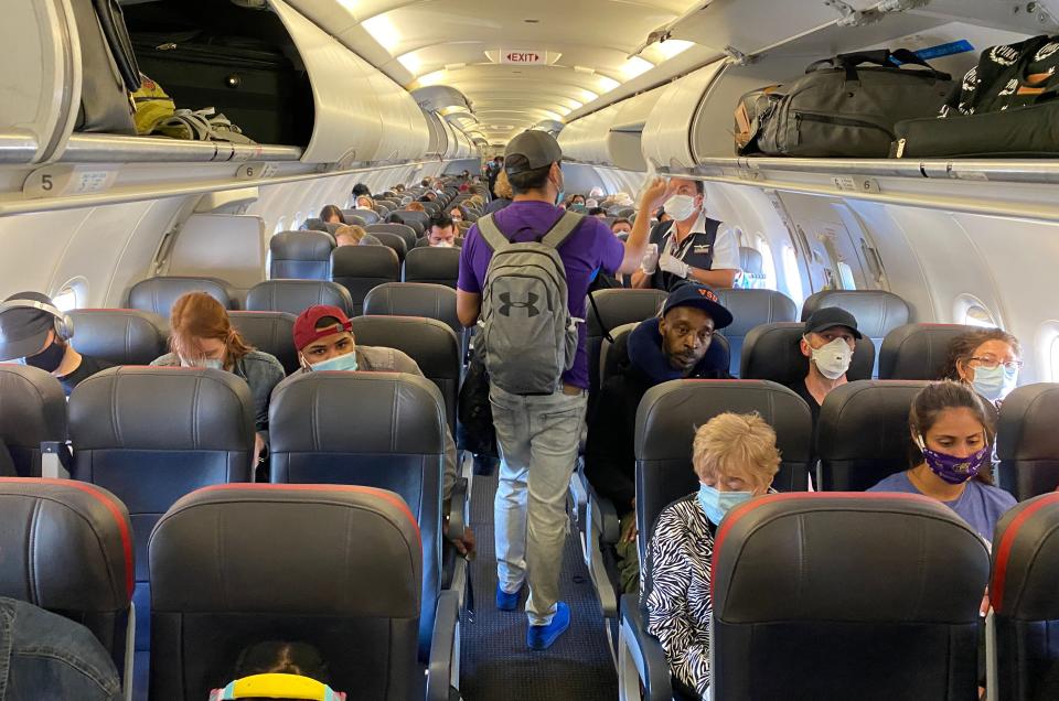 Passengers, almost all wearing facemasks, board an American Airlines flight to Charlotte, on May 3, 2020, in New York City. - The wearing of masks to protect against the coronavirus has become such a sensitive issue in the United States that airlines are struggling to impose the practice on defiant travelers in the enclosed environment of an airplane. (Photo by Eleonore SENS / AFP) (Photo by ELEONORE SENS/AFP via Getty Images)