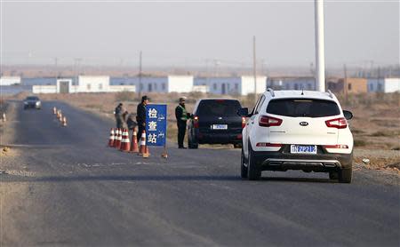 A police officer stops a car to check for identifications at a checkpoint near Lukqun town, in Xinjiang province in this October 30, 2013 file photo. REUTERS/Carlos Barria/Files