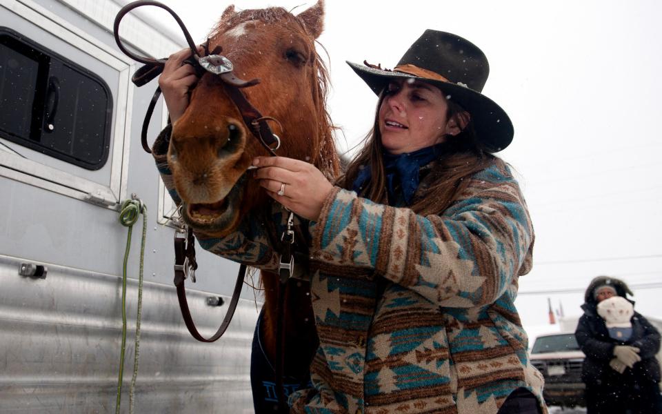 A woman in Leadville saddles up her horse ahead of the competition