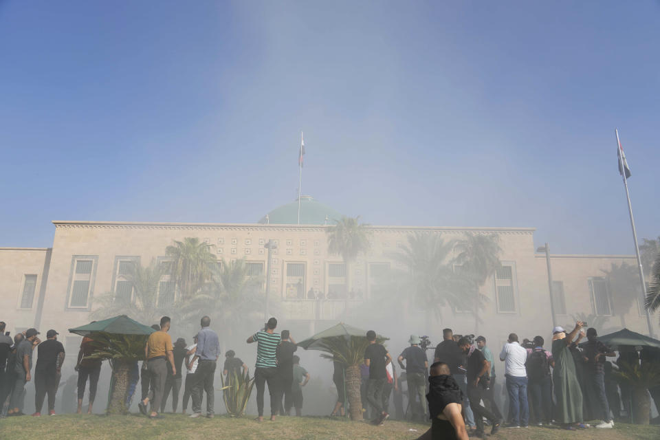 Iraqi security forces fire tear gas on followers of Shiite cleric Muqtada al-Sadr protesting inside the government palace grounds, in Baghdad, Iraq, Monday, Aug. 29, 2022. Al-Sadr, a hugely influential Shiite cleric announced he will resign from Iraqi politics and his angry followers stormed the government palace in response. The chaos Monday sparked fears that violence could erupt in a country already beset by its worst political crisis in years. (AP Photo/Hadi Mizban)