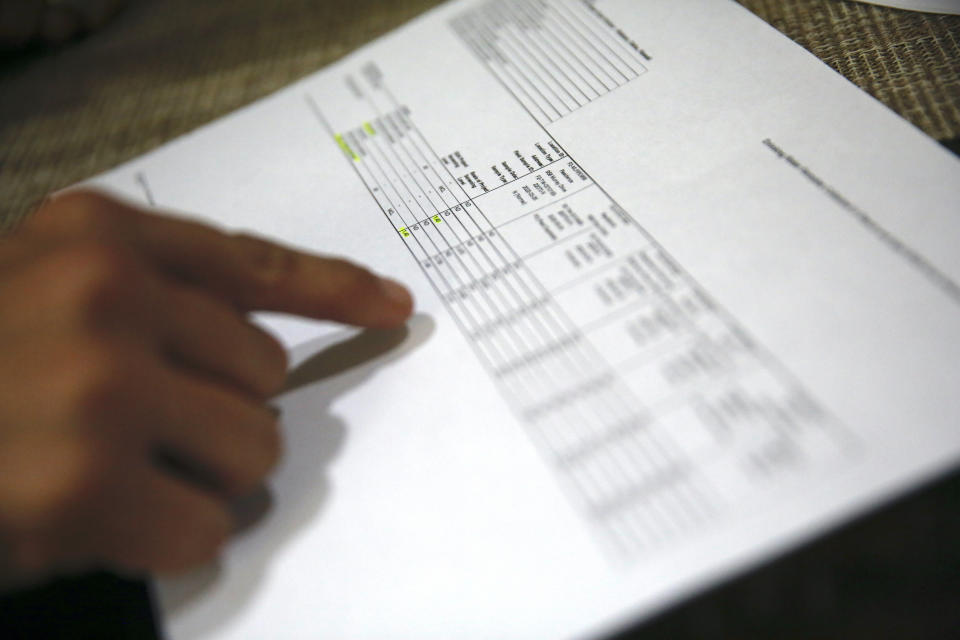 Lauren Wright, a Navy spouse whose family was sickened by jet fuel in their tap water, looks over water test results at her home in Honolulu, Friday, July 1, 2022. A Navy investigation says shoddy management and human error caused fuel to leak into Pearl Harbor's tap water last year. The leak poisoned thousands of people and forced military families to evacuate their homes for hotels. (AP Photo/Caleb Jones)