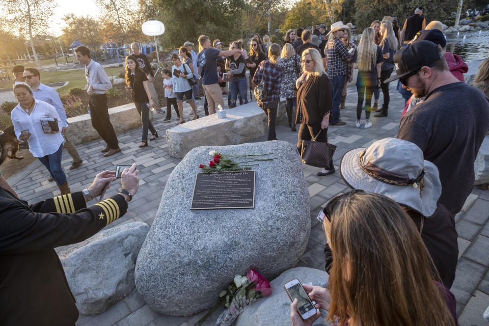 People stand near a plaque with the names of victims during the dedication of the Borderline Healing Garden at Conejo Creek Park in Thousand Oaks, Calif., Thursday, Nov. 7, 2019. The dedication marked the anniversary of a fatal mass shooting at a country-western bar a year earlier. (Hans Gutknecht/The Orange County Register via AP)