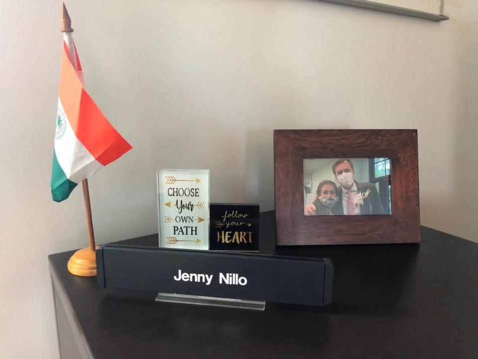 La oficina de Jenny Nillo en el edificio Omni CRA está casi vacía, incluyendo un escritorio con muy pocos objetos. En el escritorio hay una placa con su nombre, algunas citas de motivación, una bandera de la ciudad de Miami, una caja de tarjetas de presentación sin abrir y una foto enmarcada de ella y Alex Díaz de la Portilla.