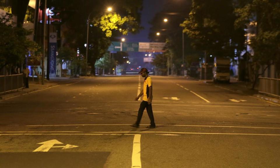 A man walks across a deserted street during a curfew in Colombo