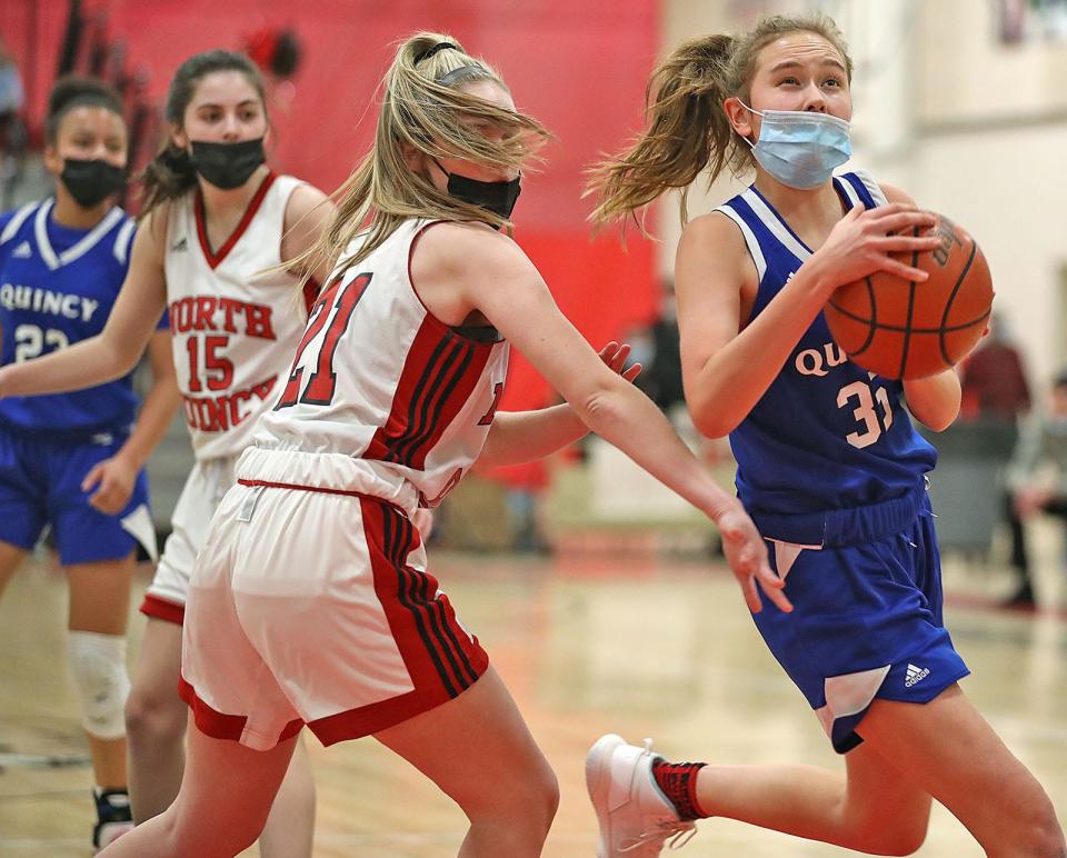 Quincy's Caroline Tracey prepares to take a shot under pressure from North Quincy's Jillian Jaehnig during a game on Friday, Jan. 21, 2022.