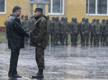 Ukraine's President Petro Poroshenko (L) shakes hands with a serviceman of Ukrainian National Guard during an opening ceremony of joint military exercise "Fearless Guardian 2015" at the International Peacekeeping Security Center near the village of Starychy western Ukraine, April 20, 2015. REUTERS/Gleb Garanich