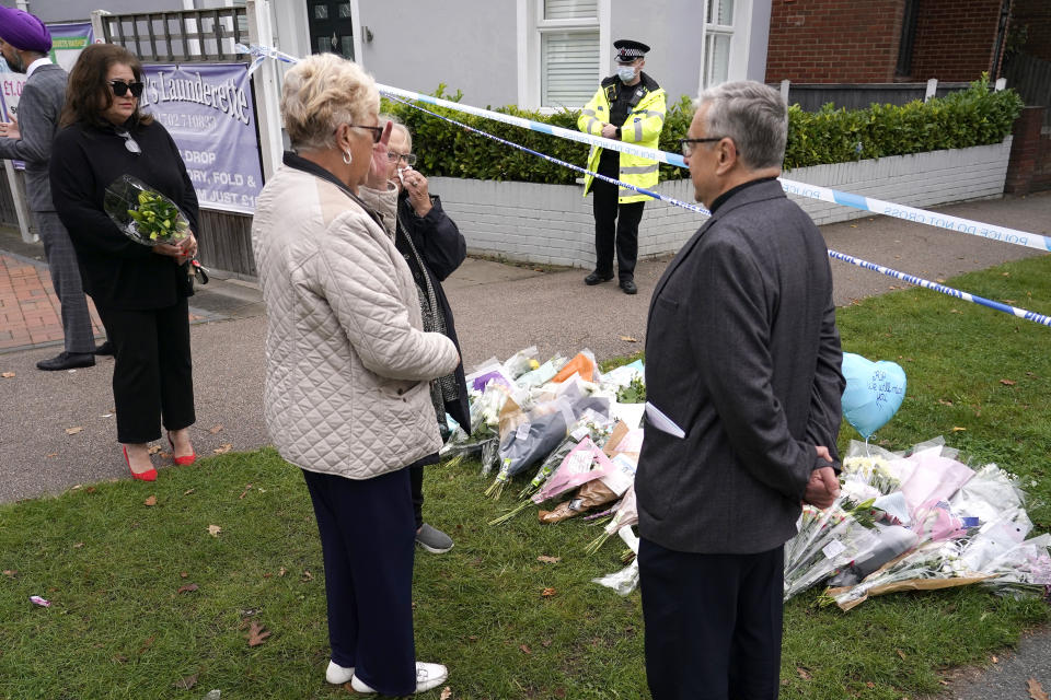 People gather by a floral tribute on the road leading to the Belfairs Methodist Church in Eastwood Road North, in Leigh-on-Sea, Essex, England, Saturday, Oct. 16, 2021. David Amess, a long-serving member of Parliament was stabbed to death during a meeting with constituents at a church in Leigh-on-Sea on Friday, in what police said was a terrorist incident. A 25-year-old man was arrested in connection with the attack, which united Britain's fractious politicians in shock and sorrow. (AP Photo/Alberto Pezzali)