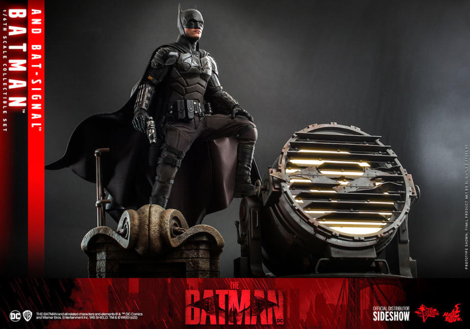 Hot Toys' The Batman figure standing next to the Bat-Signal