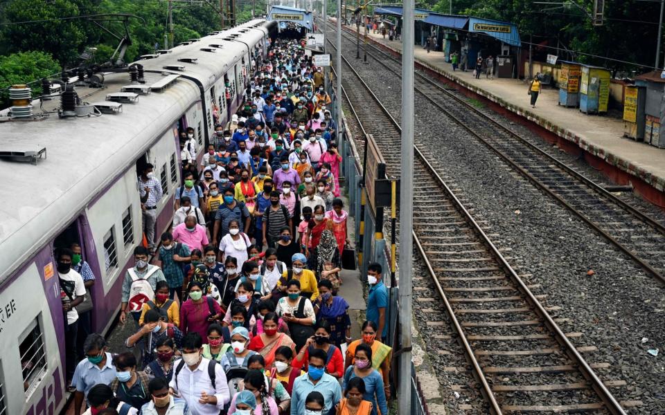 Commuters walk along a platform after arriving in a special service local train following restrictions of public transportation as a part of the ongoing lockdown in West Bengal state - AFP