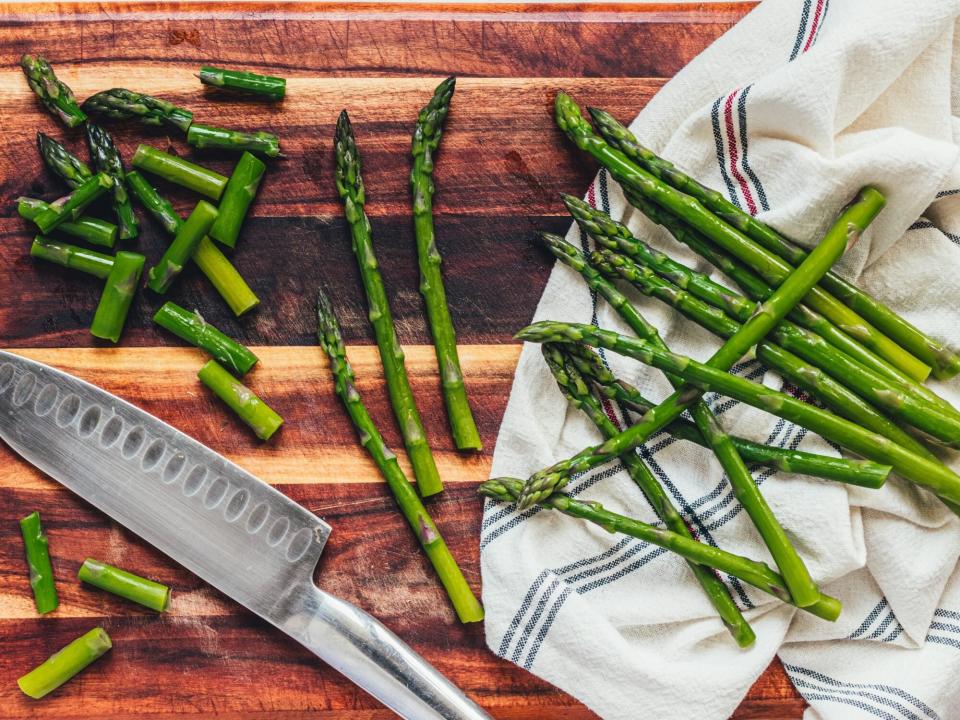 several spears of blanched asparagus being cut down into smaller pieces