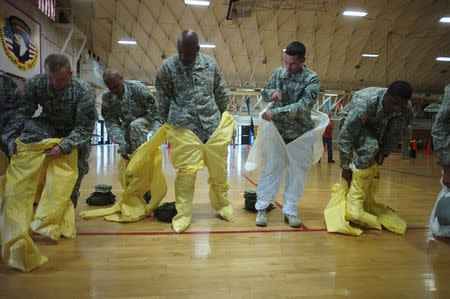 U.S. Army soldiers from the 101st Airborne Division (Air Assault), who are earmarked for the fight against Ebola, put on protective suits during training before their deployment to West Africa, at Fort Campbell, Kentucky October 9, 2014. REUTERS/Harrison McClary