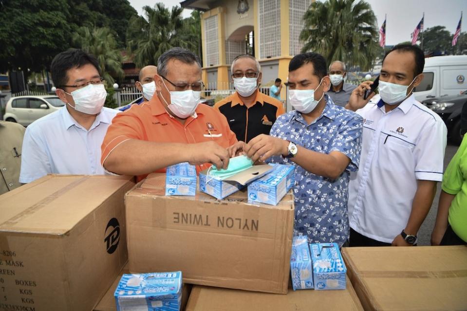 Johor Education, Human Resource, Science and Technology Committee chairman Aminolhuda Hassan examines some of the 50,000 face masks that will be distributed to schools in Tangkak and Muar, in Tangkak September 14, 2019. — Bernama pic