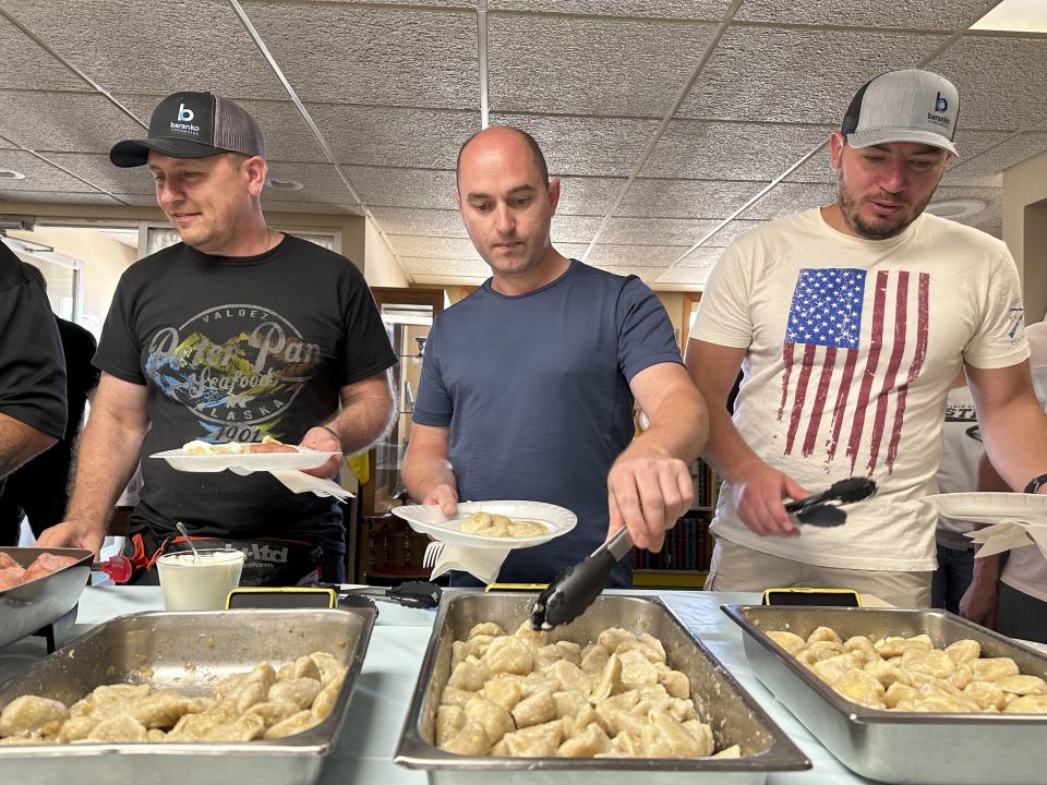 FILE - Maksym Bunchukov, Andrii Hryshchuk and Ivan Sakivskyi help themselves to perogies at a lunch hosted Monday, July 17, 2023, by the Ukrainian Cultural Institute in Dickinson, North Dakota. The North Dakota Petroleum Council's Bakken Global Recruitment of Oilfield Workers program placed about 60 Ukrainians with 16 employers throughout western North Dakota from July to November 2023, Council President Ron Ness said. The group shelved the program due to lack of demand from companies, he said. (AP Photo/Jack Dura, File)
