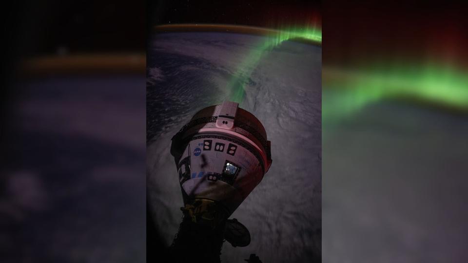 a cone-shaped spacecraft in front of a green aurora above the earth, which is in shadow