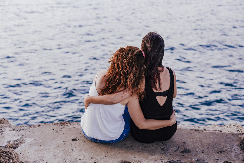 Two women on beach with arms around each other