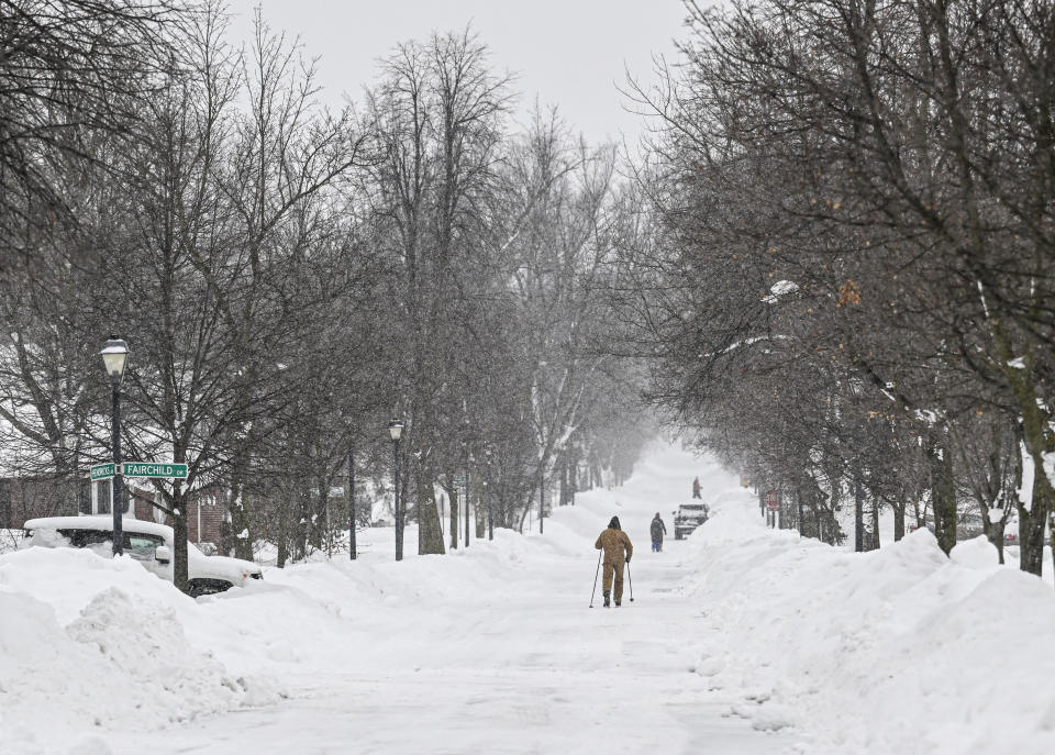A man walks on a snow-covered sidewalk in Buffalo