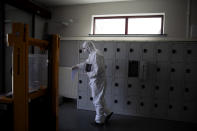 A worker in protective gear carries an urn of ashes of a Covid-19 deceased at the Pontes crematorium and funeral center in Wilrijk, Belgium, Friday, April 3, 2020. At the Wilrijk crematorium, near Antwerp, an extra 200 cremations due to Covid-19 have been done since the start of the week. The new coronavirus causes mild or moderate symptoms for most people, but for some, especially older adults and people with existing health problems, it can cause more severe illness or death. (AP Photo/Virginia Mayo)