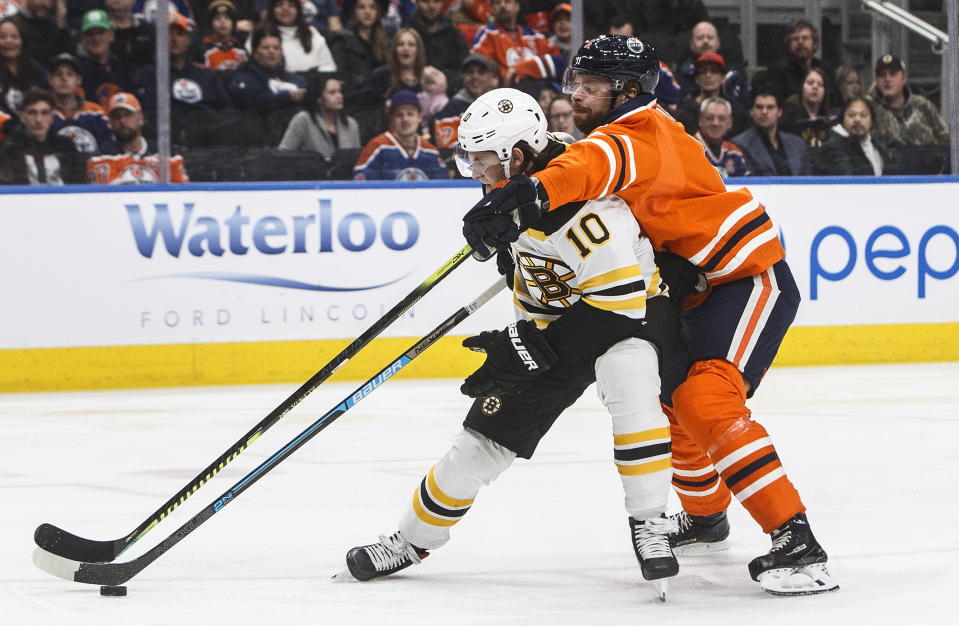 Boston Bruins left wing Anders Bjork (10) and Edmonton Oilers defenseman Adam Larsson (6) battle for the puck during the first period of an NHL hockey game, Wednesday, Feb. 19, 2020 in Edmonton, Alberta. (Jason Franson/The Canadian Press via AP)