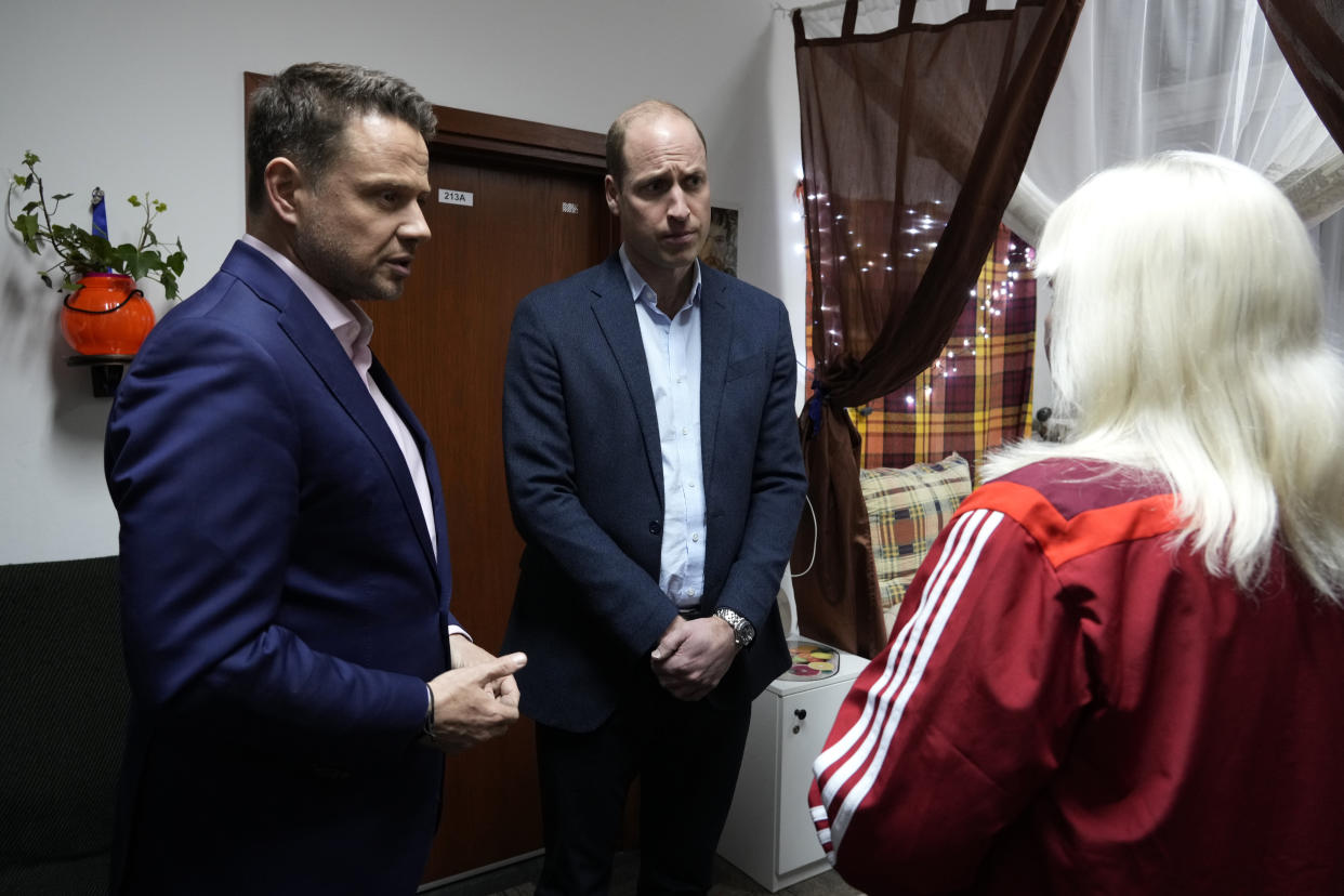 Britain's Prince William, center, and Mayor of Warsaw Rafal Trzaskowski, left, talk to an Ukrainian woman, who have fled the war, during their visit to an accommodation centre in Warsaw, Poland, Wednesday, March 22, 2023. (AP Photo/Czarek Sokolowski)