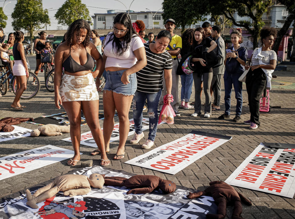 People read signs placed on the ground during a protest against a police raid that killed more than a dozen of people in Guaruja, Sao Paulo state, Brazil, Wednesday, Aug. 2, 2023. The death toll from the raid has climbed to at least 14, in a sprawling operation that has raised questions about the use of lethal force by police. (AP Photo/Tuane Fernandes)