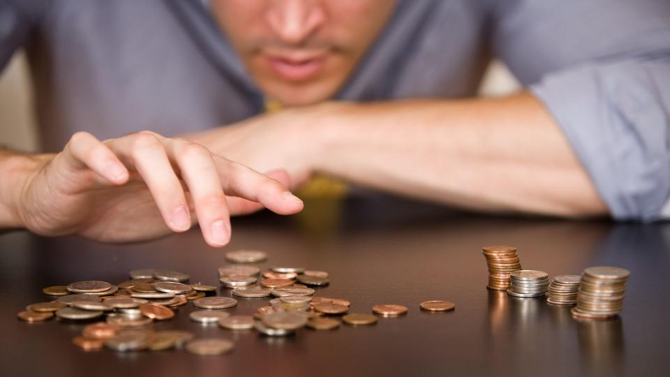 A man counts his coins on a tabletop.