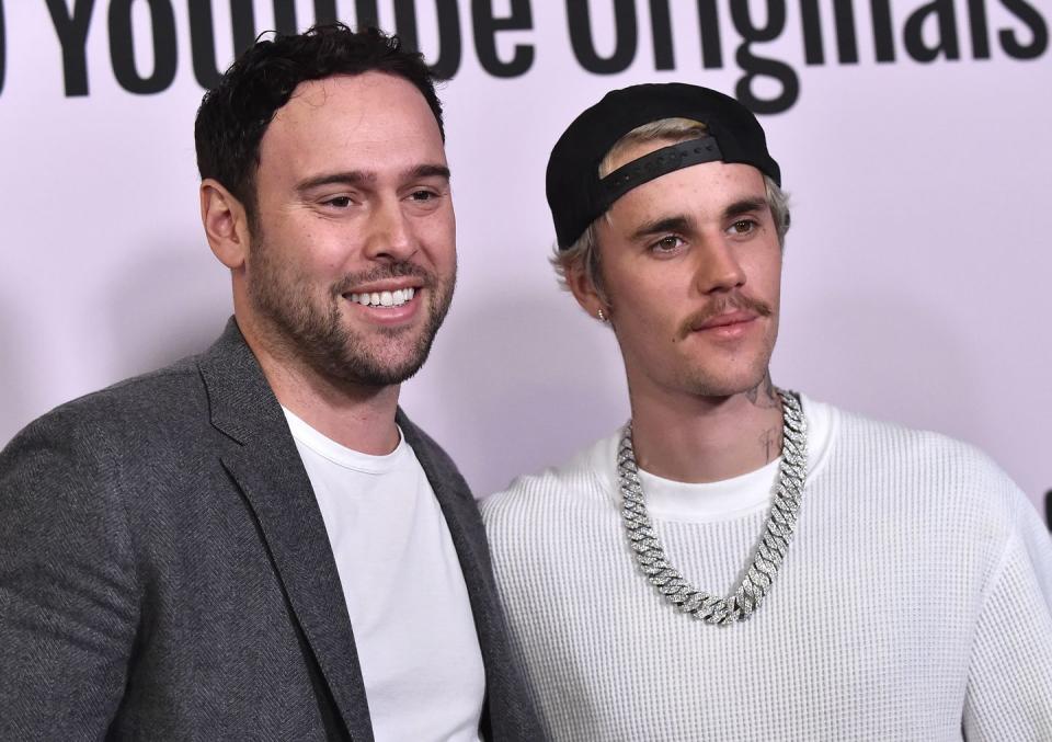 scooter braun embracing justin bieber with his left arm in a photo