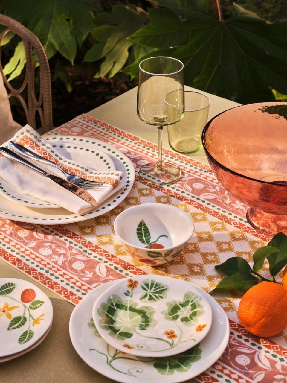 a table dressed with orangery patterned runner and decorative plates and green glasses