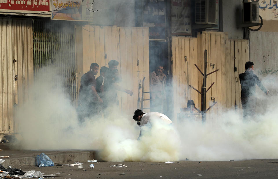 An anti-government protester prepares to throw back a tear gas canister fired by police during clashes at Khilani Square in Baghdad, Iraq, Thursday, Nov. 14, 2019. (AP Photo/Hadi Mizban)