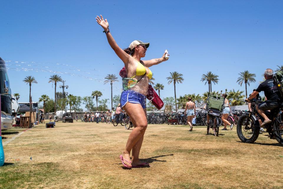 Laura Burgues of Murrieta cools off with some water being sprayed by RV campers along the path to the Stagecoach country music festival at the Empire Polo Club in Indio, Calif., on Friday, April 28, 2023.