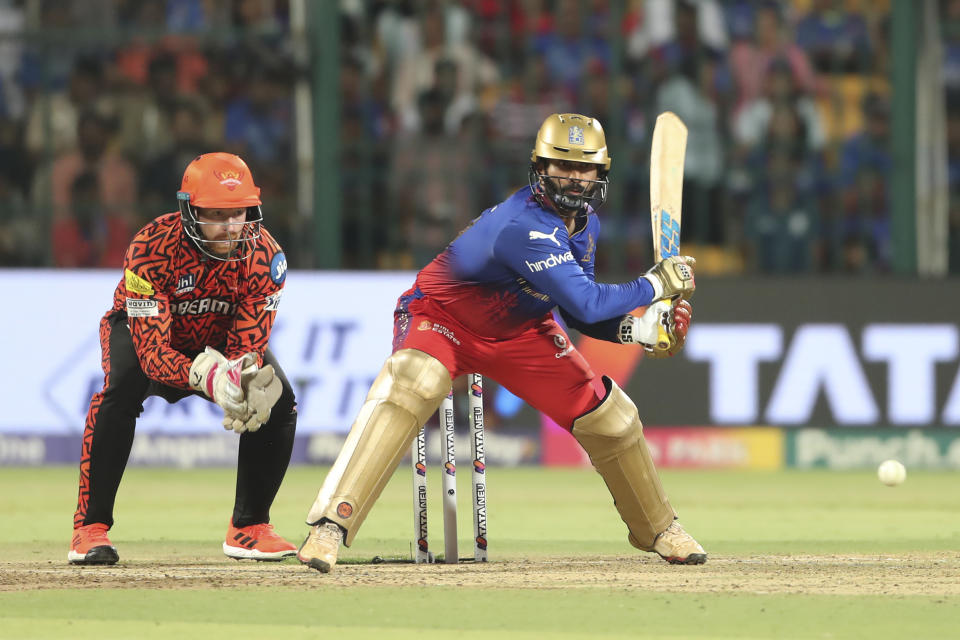 Royal Challengers Bengaluru's Dinesh Karthik plays a shot as Sunrisers Hyderabad's Heinrich Klaasen watches during the Indian Premier League cricket match between Royal Challengers Bangaluru and Sunrisers Hyderabad in Bengaluru, India, Monday, April 15, 2024. (AP Photo/Kashif Masood)