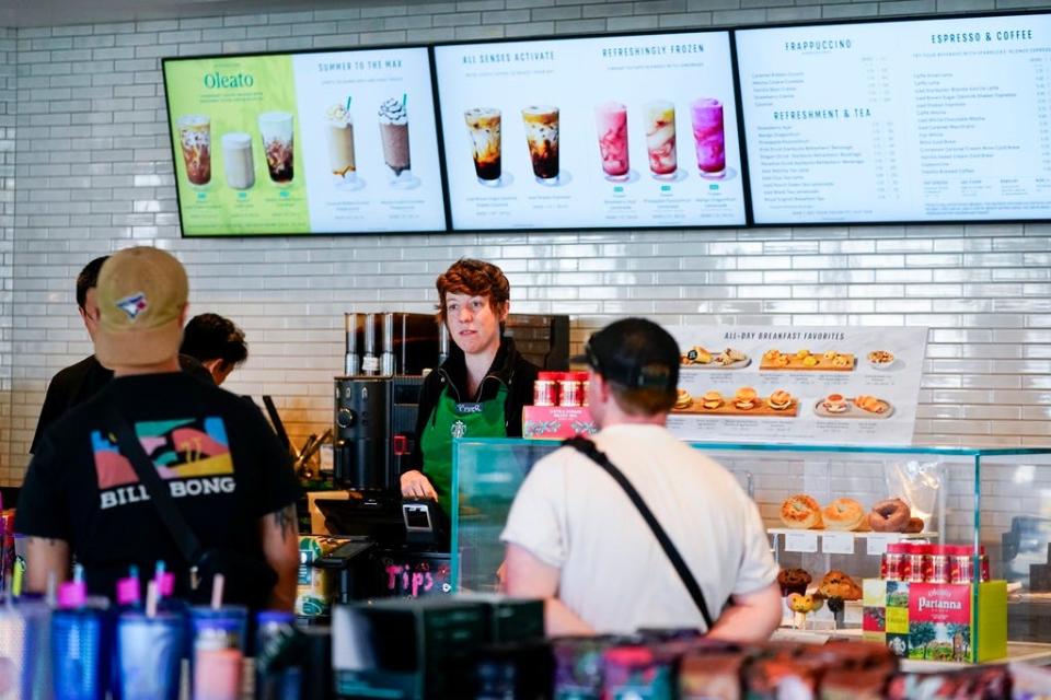 Workers at a Starbucks with a menu overhead.