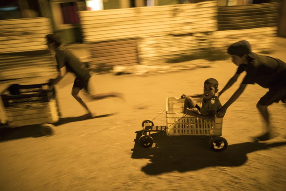 In this Nov. 19, 2019 photo, children race in makeshift go-carts in the "Altos de Milagros Norte" neighborhood of Maracaibo, Venezuela. Nationwide, an estimated 4.5 million residents have fled Venezuela, most going to nearby Colombia, Peru and Ecuador. They search for better jobs to send money home, but they often confront backlash and hardships as their numbers steadily grow. (AP Photo/Rodrigo Abd)